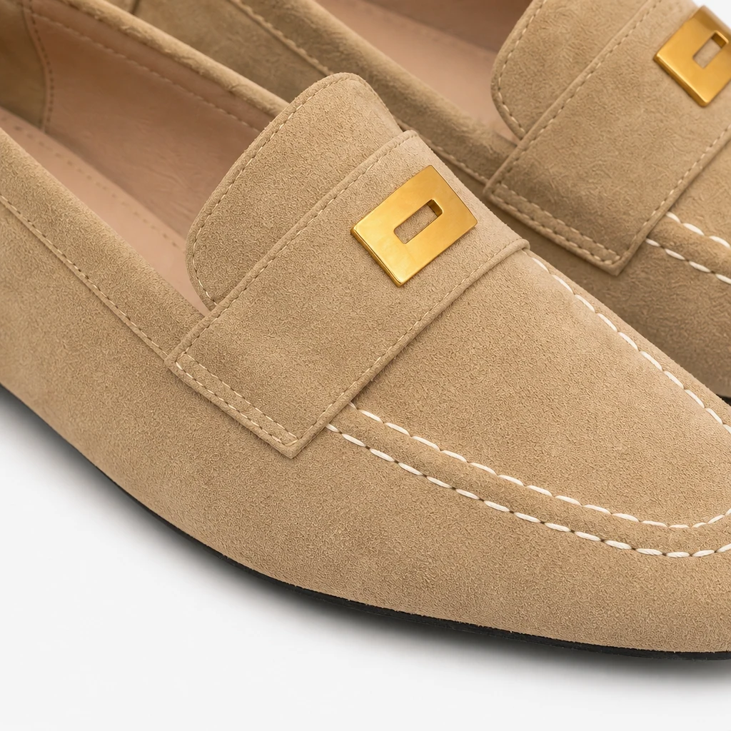 Gros plan sur la texture, les coutures et les accents métalliques des mocassins d'aspect suède