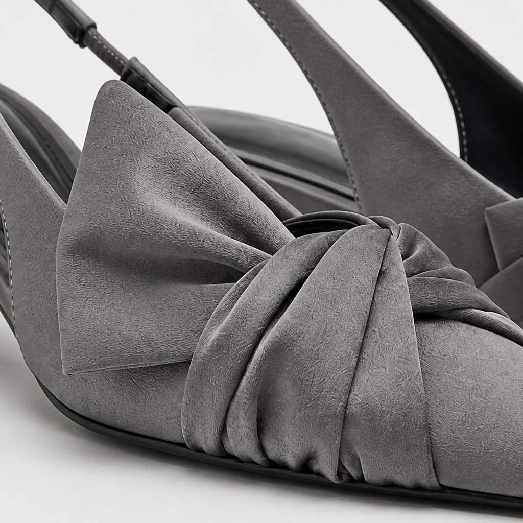 Close-up of grey slingback pump material, bow detail, pointed toe, and heel construction